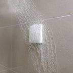 Wireless Kinetic Switch in a square showerhead on a tiled wall with water droplets