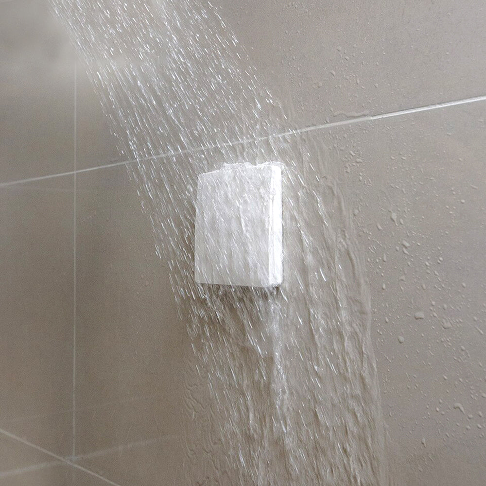 Wireless Kinetic Switch in a square showerhead on a tiled wall with water droplets