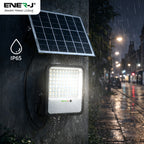 Solar street light on a wet sidewalk with raindrops, featuring Ener-J branding and IP65 rating.