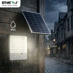 Solar light fixture on a building exterior with a dark sky and cobblestone street.